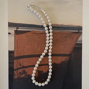 Close-up of minimalist pearl necklace with elegant silver curved hook clasp detail