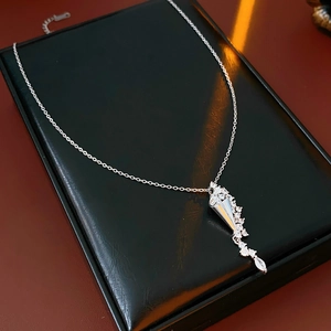 Macro shot of silver hourglass pendant with zircons on a black leather jewelry box