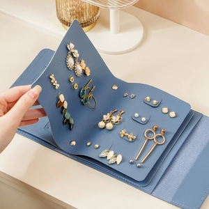 Close-up of blue leather jewelry organizer showing earring holes and necklace hooks in detail