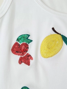 Close-up of white ribbed fabric with detailed sequin lemon and red flower embroidery