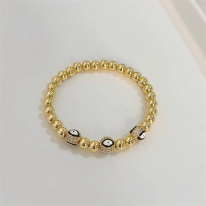 Macro shot of 18K gold beaded stretch bracelet with micro-pave evil eye charms