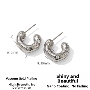 Close-up of silver C-shaped stainless steel earrings with sparkling zircon inlay details