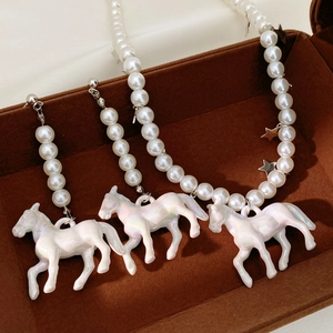 Macro shot of pearl necklace and horse pendant in a brown velvet jewelry box