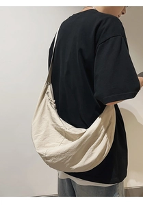 Grand sac bandoulière croissant en nylon crème porté par un mannequin sur un t-shirt