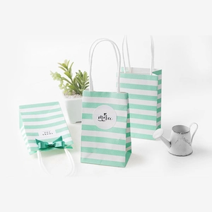 Three green striped white kraft paper gift bags with handles and decorative ribbons