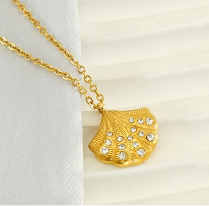Detailed close-up of golden shell pendant necklace with sparkling crystal inlay details