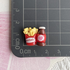 Dettaglio di patatine e bevande in miniatura in resina su tappetino graduato CM