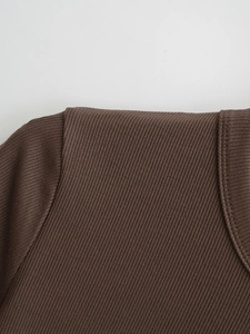 Gros plan détaillé sur la texture en maille côtelée marron foncé et les coutures de qualité