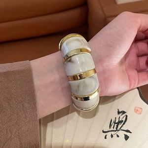 Primer plano de pulsera vintage de acrílico con textura de mármol y bordes dorados