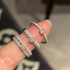 Detailed close-up of three silver-plated geometric rings with pink and white cubic zirconia