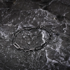 Detail of gunmetal paperclip link bracelet on a dark stone background with lobster clasp