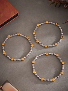 Detail of beaded stretch bracelets with textured silver beads and golden zircon flowers