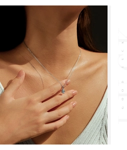Detail of silver S925 necklace featuring an oval light blue gemstone on model neck