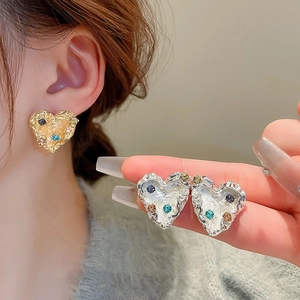 Detail of heart stud earrings with textured metallic finish and colorful center stones