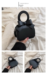 Detail view of the black handbag with a decorative bow and round cutout handle