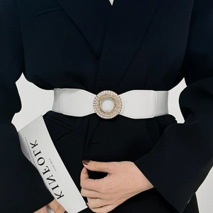 Close-up of white elastic waist belt with a sparkling rhinestone-set round gold buckle
