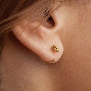 Close-up of a gold snake ear cuff wrap design on a model ear with macro detailing