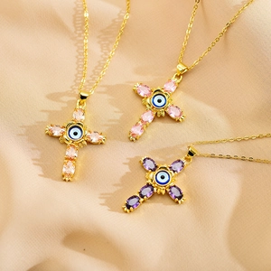 Macro detail of cross pendants with devil eye inlay and colorful cubic zirconia on silk