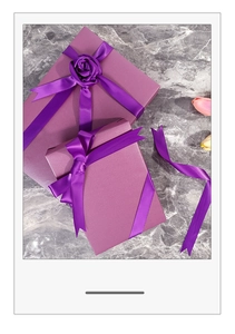 Close-up of lilac purple gift boxes with deep purple satin ribbons and rose detail
