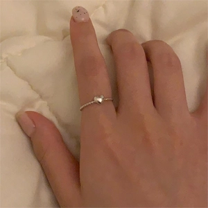 Close-up of S925 sterling silver heart ring with twisted rope band worn on a hand