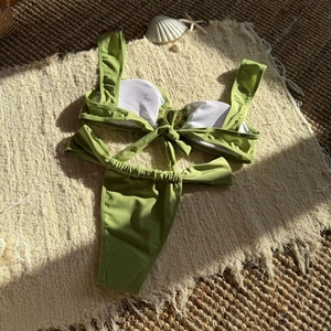 Detailed flat lay of an olive bikini with star metal charms and beach shells