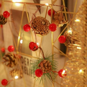 Macro detail of artificial pine needle garland with cones, red berries and LED lights