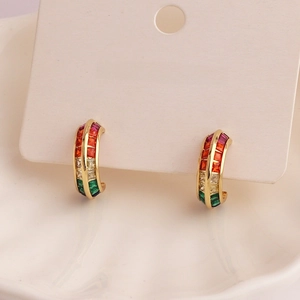 Detail view of gold C-shaped earrings with colorful pave stones on a jewelry card