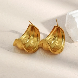 Detailed view of wide C-shaped gold-plated earrings with elegant wavy texture on stone