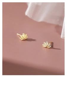 Macro detail of gold lotus flower studs on a soft pink surface with white fabric