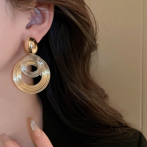 Macro view of gold multilayer geometric hoop earrings worn on a model with elegant style