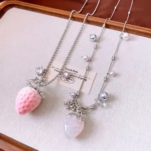 Sweet strawberry pendant necklace with pearls and rhinestones on a rustic wooden tray