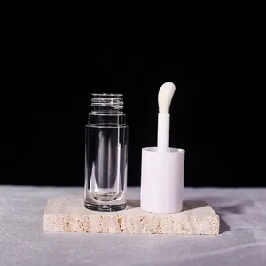 Macro shot of 6ml transparent lip gloss tube with wide applicator brush on stone stand