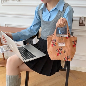 Detail of corduroy tote bag featuring Keep Smiling text and metal snap closure