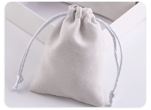 Close-up of soft beige microfiber drawstring jewelry pouch showing velvet texture