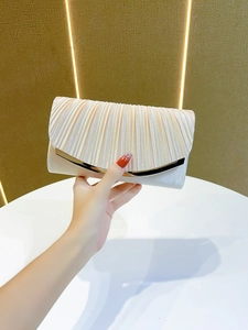 Detail view of champagne pleated silk evening clutch with elegant gold metal trim