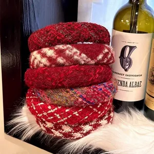 Close-up of padded tweed headbands in festive red and beige on a soft faux fur backdrop