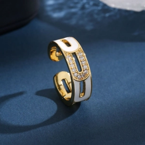 Gold open ring with white enamel inlay and sparkling crystals on a blue texture