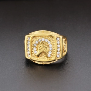 Macro shot of gold horse head ring with white rhinestones on a dark textured surface