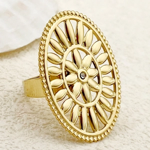 Close-up of golden hollow oval ring with floral motif and center zircon stone
