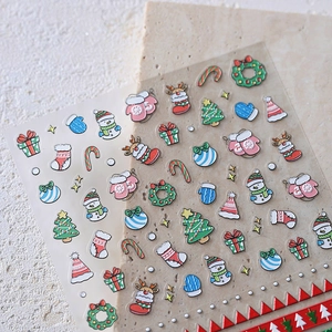 Embossed Christmas nail stickers with snowman and tree patterns on stone background