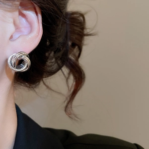 Gros plan de boucles d'oreilles rondes évidées argentées portées par un mannequin