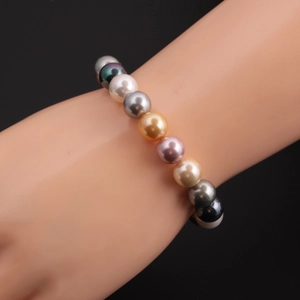 Nahaufnahme von bunten Muschelperlenarmbändern an einem Modelldisplay auf schwarzem Grund