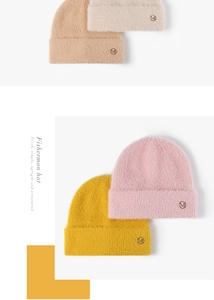 Detail of soft winter knit beanies with fluffy feather yarn and metal M logo