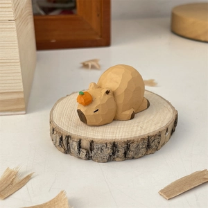 Close-up of hand-carved wooden capybara ornament with an orange on its head