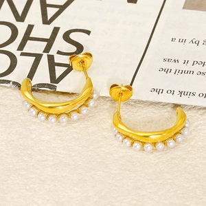 Detailed close-up of gold geometric hoop earrings with pearls on vintage background