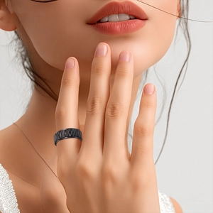 Modern black matte stainless steel ring with geometric diamond texture on a model hand