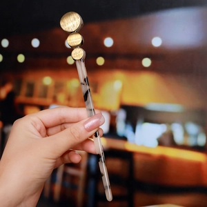 Detail of a tortoiseshell acetate hair pin featuring three golden metal round accents