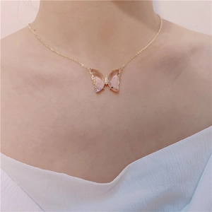 Close-up of a gold butterfly crystal pendant necklace worn on a model neckline