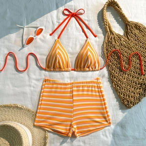 Flat lay of striped orange and white bikini set with drawstring shorts and matching accessories