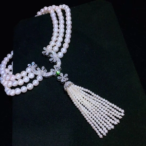 Detailed view of triple-layer pearl necklace with floral zircon clasp and long tassels